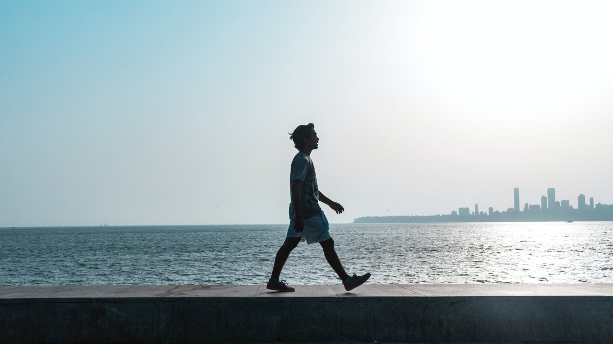 Image of a man walking along the beach in the sunlight