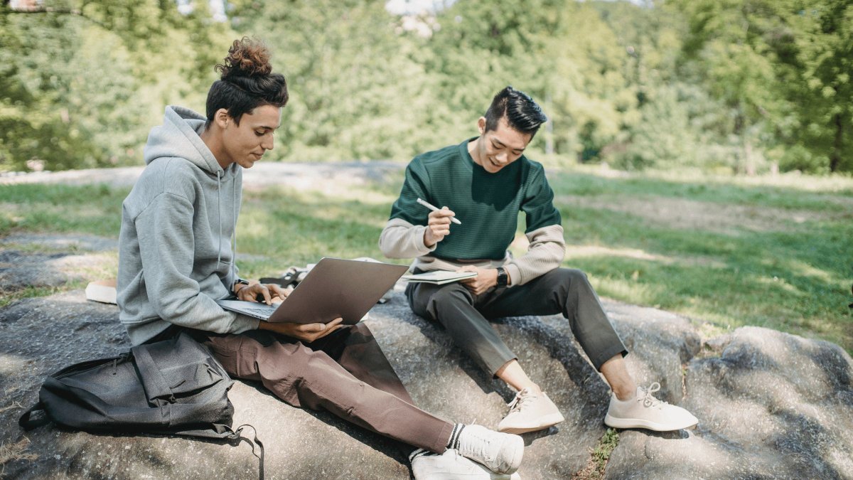 Two young people sitting outside working on a paper