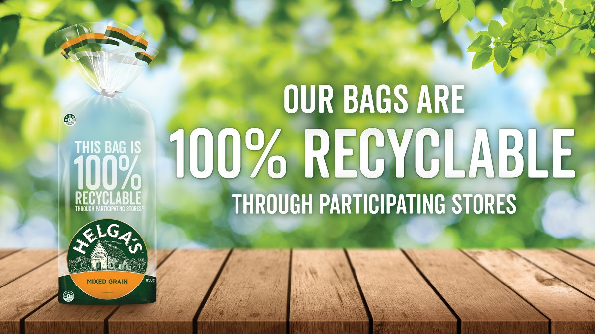 Image of a Helga's Bakehouse bread bag on a wooden platform with greenery in the background, displaying the message "Our bags are 100% recyclable through participating stores"